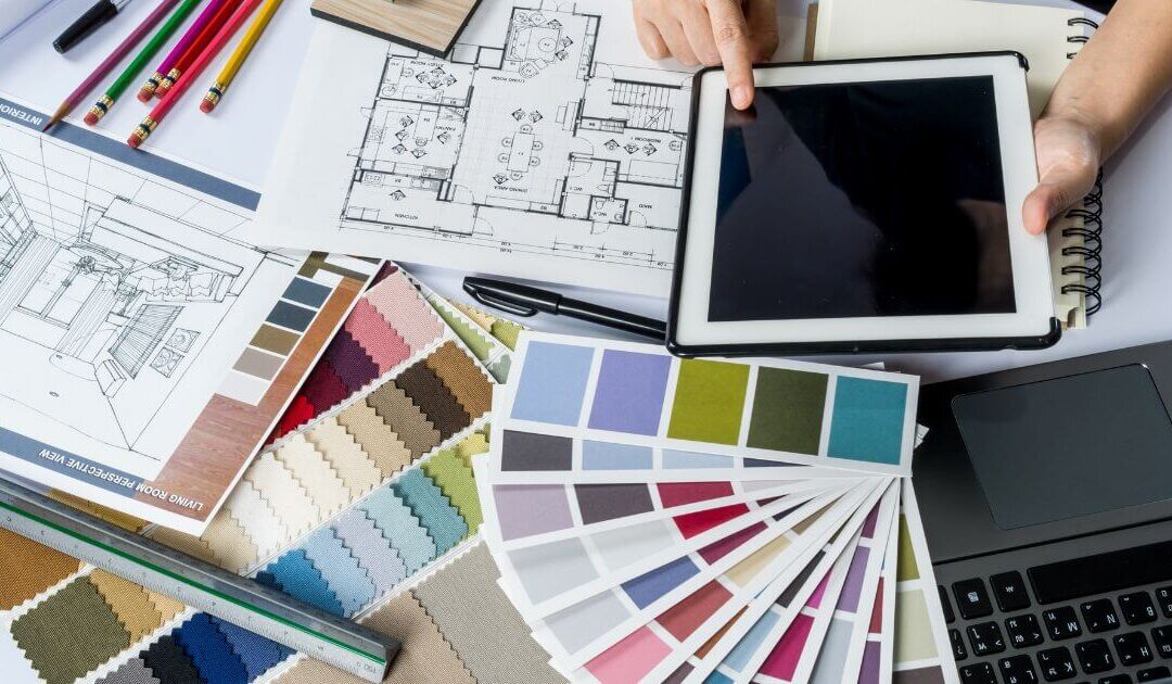 Persons hands at desk with various items whilst studying a how to become an interior designer course