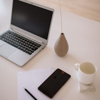 Close up of a laptop, mug and mobile phone which is turned off