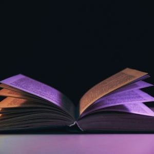 Beautiful open old book in the colour light on a table and night background.