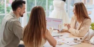 A couple looks at a calendar with their wedding planner as she explains what does a wedding planner do