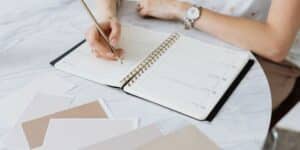 A wedding planner sat a desk planning a timeline in a diary